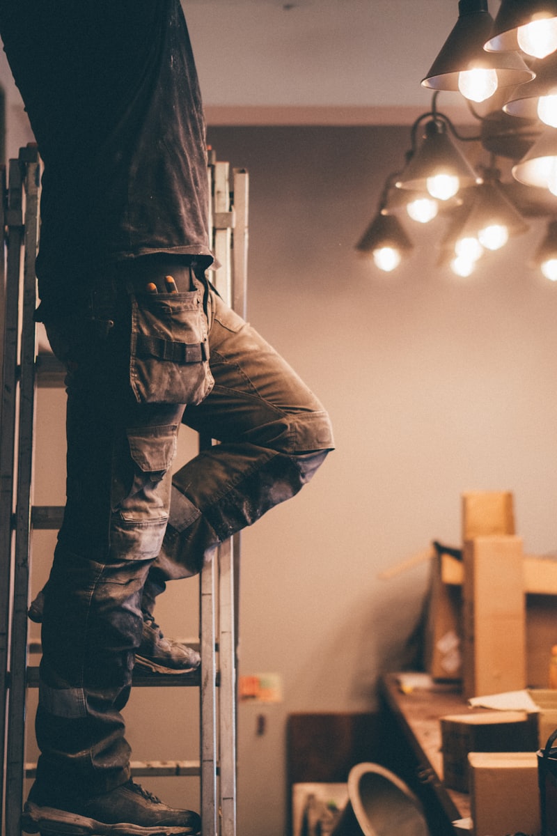 Electrician installing a light fixture in a home